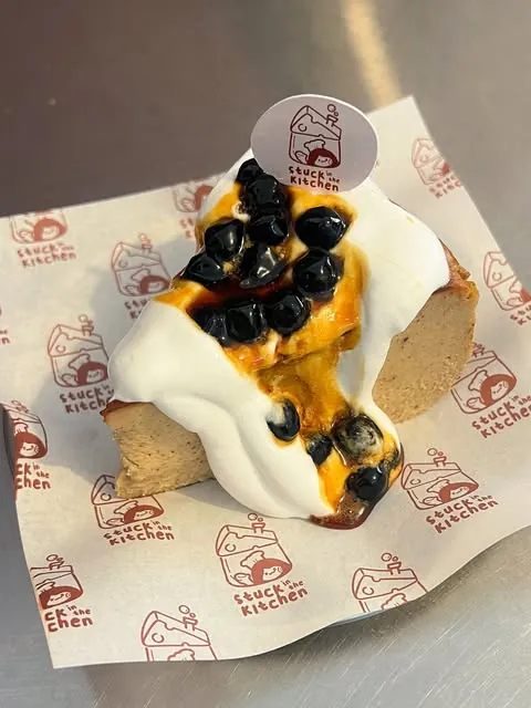 A special cheesecake topped with cream and blueberries on paper printed with the SINK logo