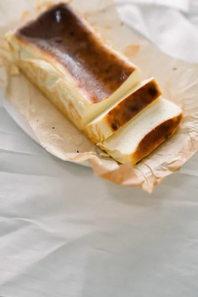 An Original cheesecake loaf, cut, on crinkled baking paper
